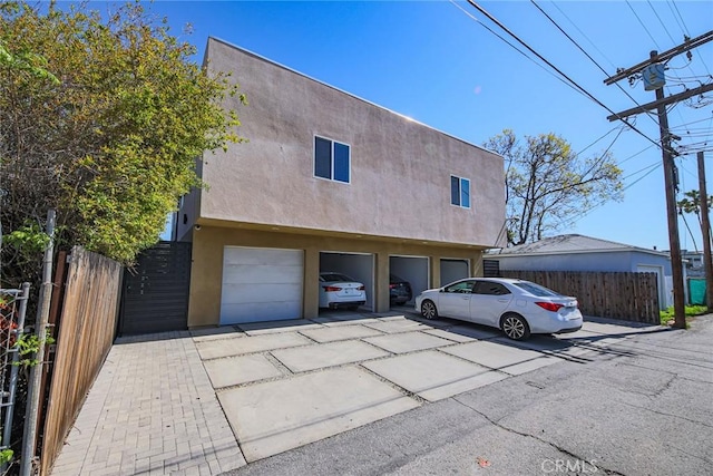 7443 Troost Ave, North Hollywood, CA 91605 - view of front of home with a garage, driveway, stucco siding, and fence