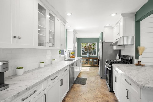 kitchen featuring under cabinet range hood, appliances with stainless steel finishes, a sink, and white cabinetry