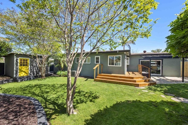 back of property featuring a patio, a deck, a yard, and stucco siding