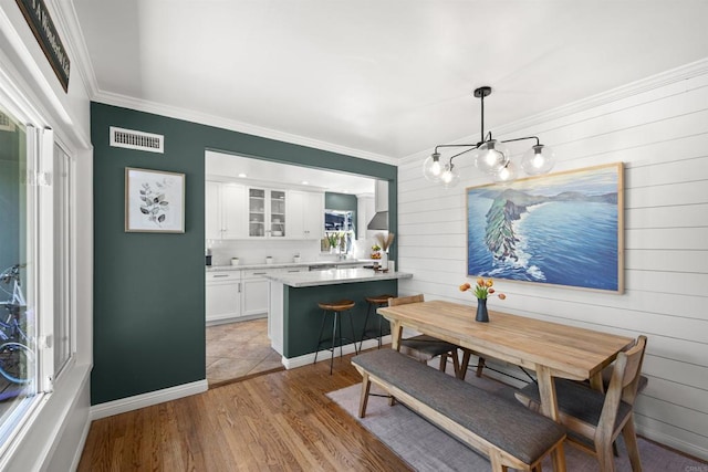dining space featuring ornamental molding, a notable chandelier, visible vents, and light wood-type flooring