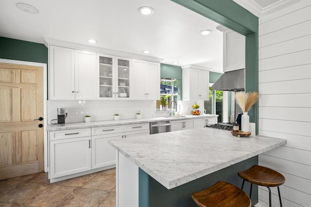 kitchen with white cabinets, a kitchen bar, backsplash, and stainless steel dishwasher