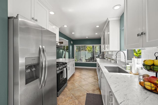 kitchen featuring range with gas stovetop, tasteful backsplash, a sink, white cabinets, and stainless steel refrigerator with ice dispenser