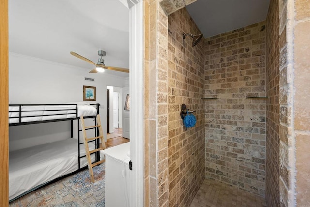 bathroom featuring ceiling fan, ornamental molding, visible vents, and tiled shower