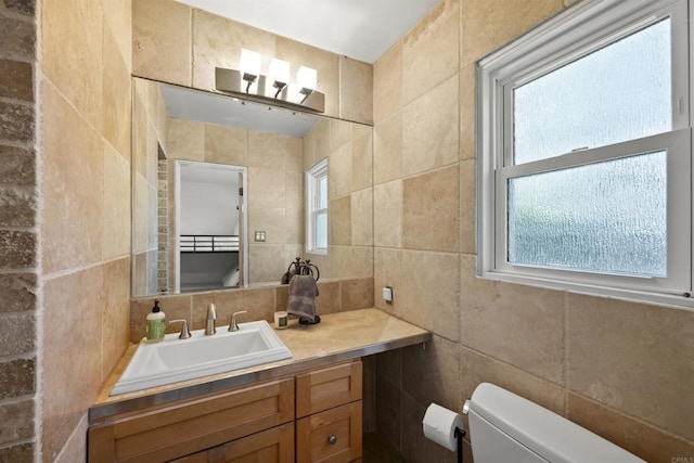 half bath with tile walls, plenty of natural light, vanity, and toilet