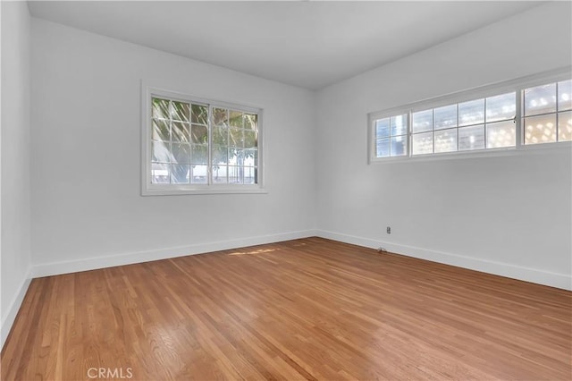 spare room featuring baseboards and light wood finished floors
