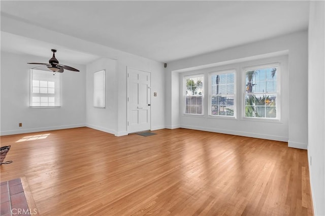 unfurnished living room featuring baseboards, light wood-style flooring, and a healthy amount of sunlight