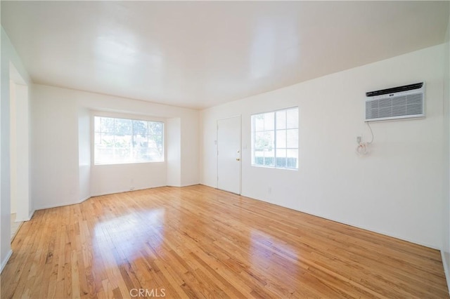 216 S Glenwood Pl, Burbank, CA 91506 - empty room with a healthy amount of sunlight, a wall mounted air conditioner, and light wood-style floors