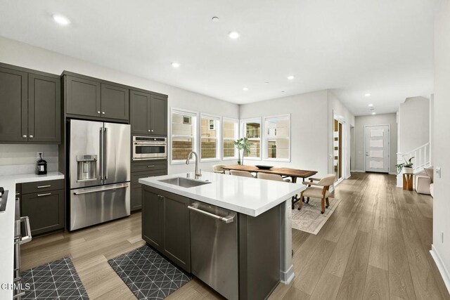 26945 Nature View Pl, Valencia, CA 91381 - kitchen featuring stainless steel appliances, a sink, light wood finished floors, a center island with sink, and light countertops
