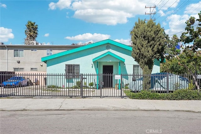 view of front facade with stucco siding, concrete driveway, and a fenced front yard