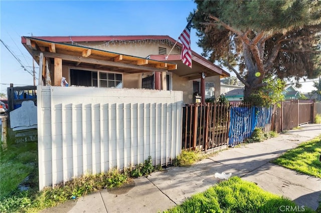 bungalow-style house featuring stucco siding and fence