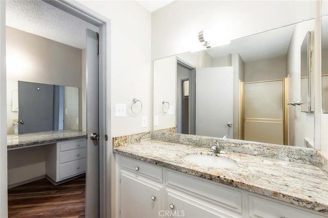 bathroom with vanity, a stall shower, and wood finished floors