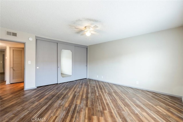 unfurnished bedroom with a ceiling fan, visible vents, wood finished floors, baseboards, and a closet