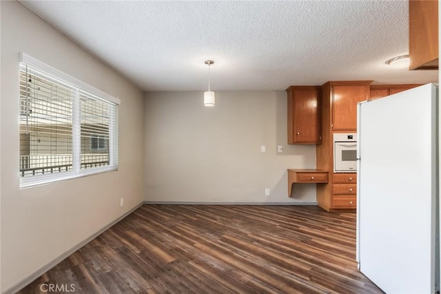 kitchen with a textured ceiling, dark wood-style floors, white appliances, and hanging light fixtures