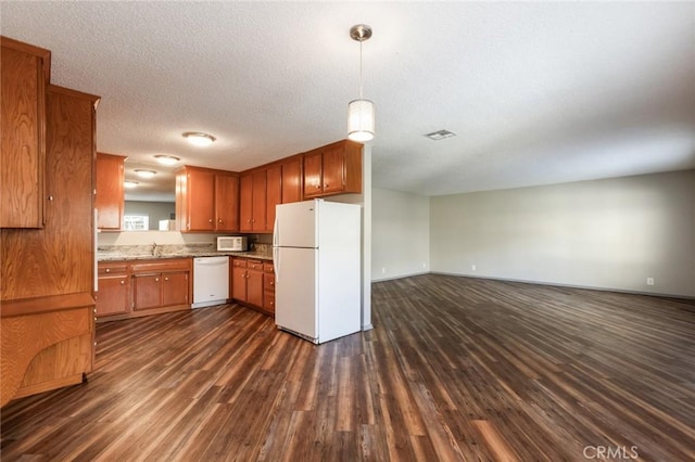 kitchen featuring white appliances, open floor plan, dark wood-type flooring, brown cabinets, and a sink