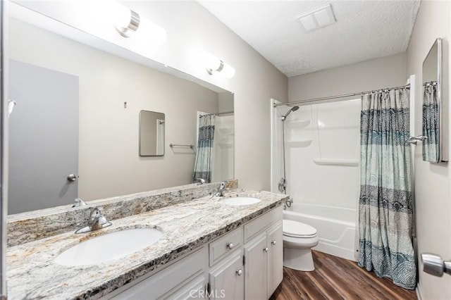 bathroom with visible vents, a sink, wood finished floors, and double vanity
