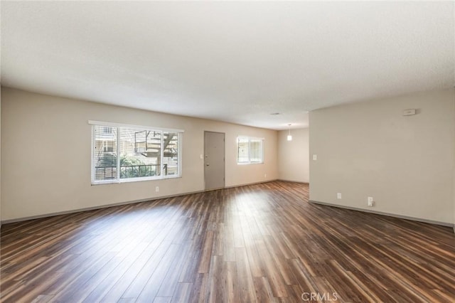 unfurnished living room featuring dark wood-style flooring and baseboards