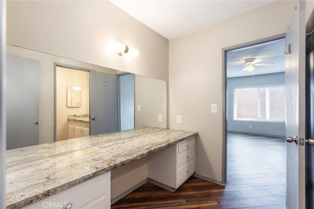 bathroom featuring ceiling fan, vanity, a textured ceiling, baseboards, and wood finished floors