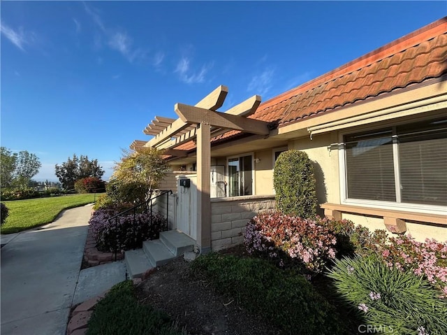 view of side of property featuring a yard, a tiled roof, and stucco siding