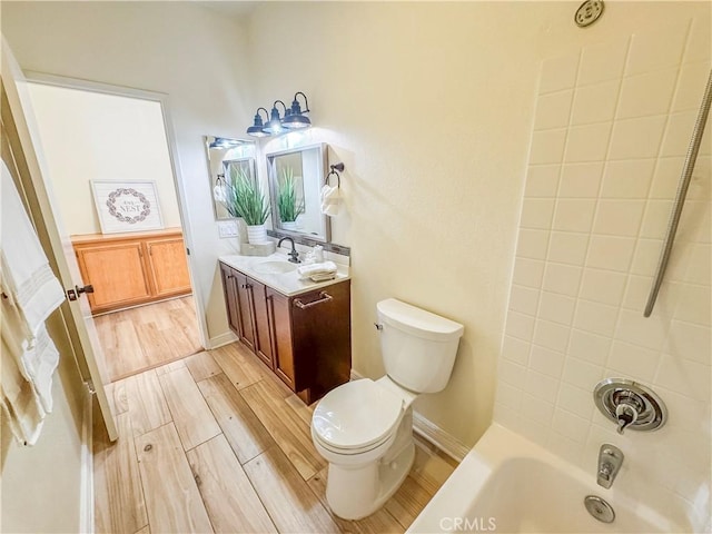 bathroom featuring toilet, vanity, wood finished floors, and bathing tub / shower combination