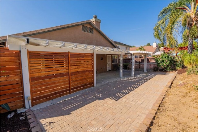 view of front facade with a chimney, a pergola, a patio, and fence private yard