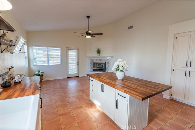 kitchen with open floor plan, ceiling fan, white cabinetry, and butcher block counters