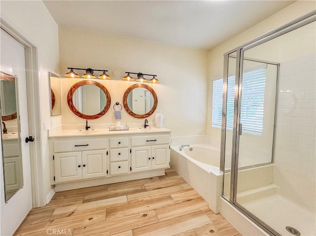 full bathroom featuring a bath, a stall shower, wood finished floors, and a sink