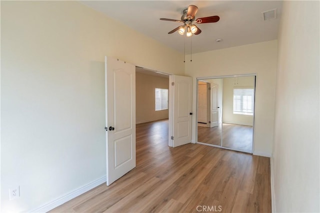 unfurnished room with baseboards, a ceiling fan, visible vents, and light wood-style flooring