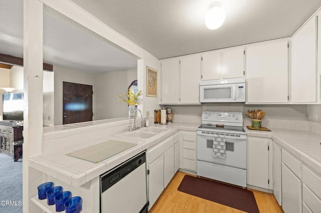 kitchen with white cabinets, tile counters, a sink, and white appliances