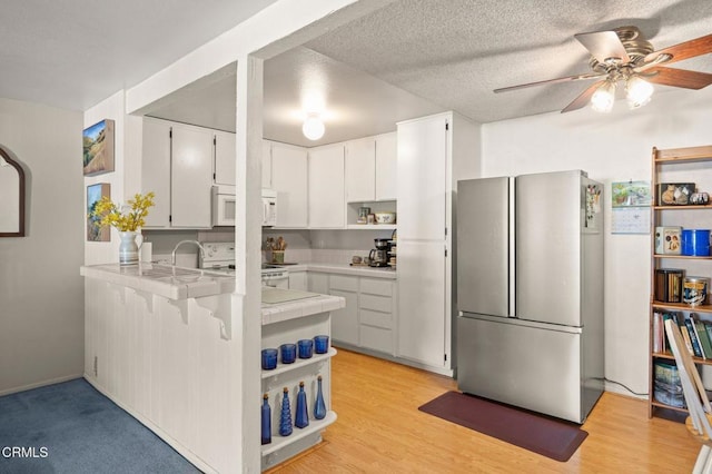 kitchen featuring open shelves, a ceiling fan, tile countertops, white appliances, and a peninsula