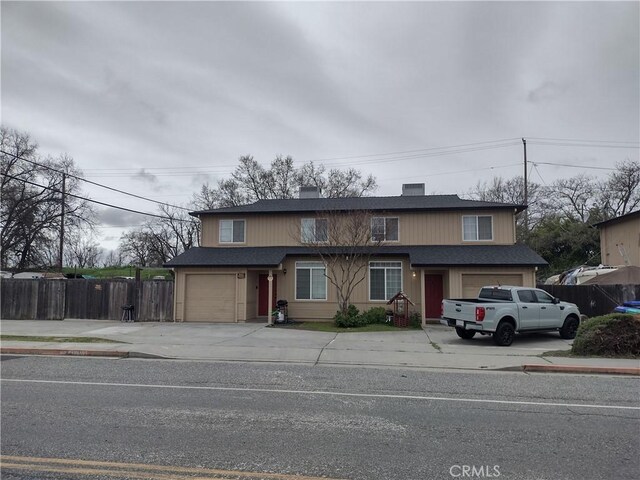 view of front facade with fence, a chimney, a garage, and concrete driveway