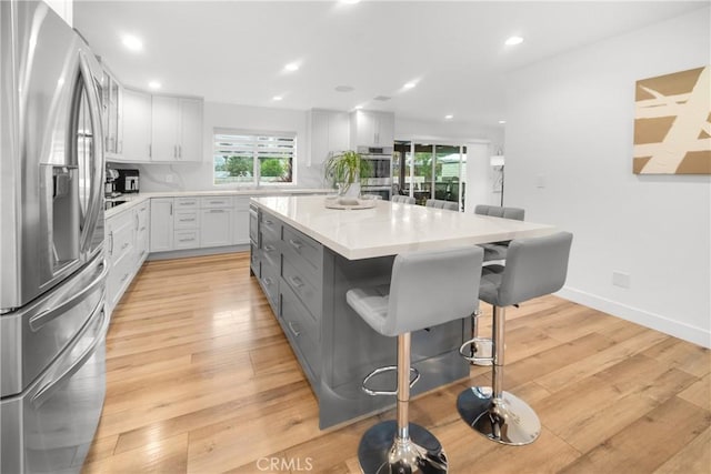 26011 Redbluff Dr, Calabasas, CA 91302 - kitchen with light wood-type flooring, a breakfast bar area, white cabinetry, light countertops, and appliances with stainless steel finishes