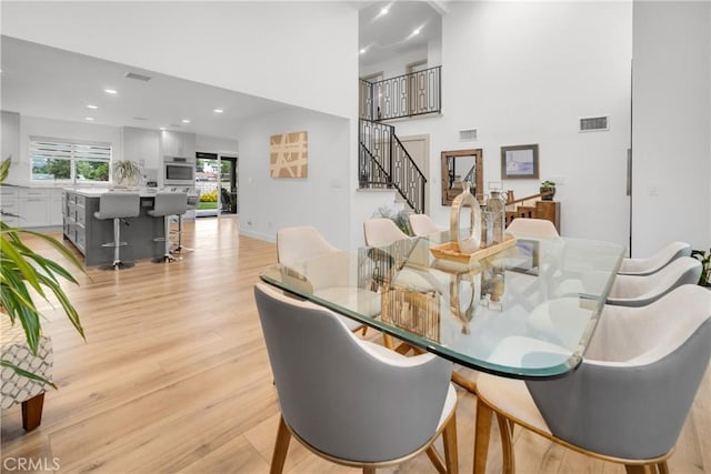 26011 Redbluff Dr, Calabasas, CA 91302 - dining room with stairway, light wood finished floors, a towering ceiling, and visible vents