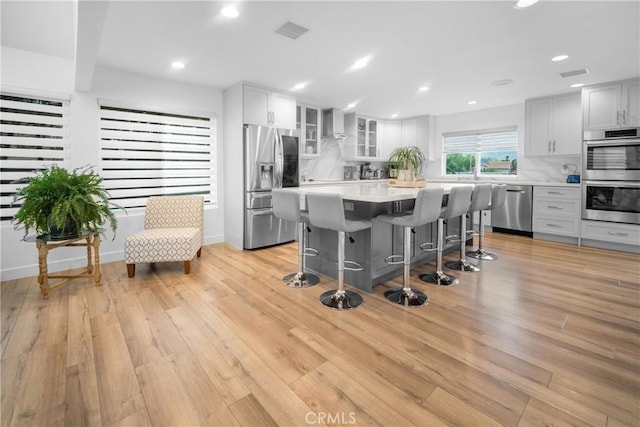 26011 Redbluff Dr, Calabasas, CA 91302 - kitchen with light wood-style flooring, stainless steel appliances, a kitchen breakfast bar, visible vents, and light countertops