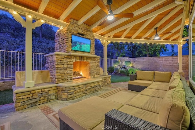 view of patio / terrace featuring a fenced backyard, an outdoor living space with a fireplace, and a ceiling fan