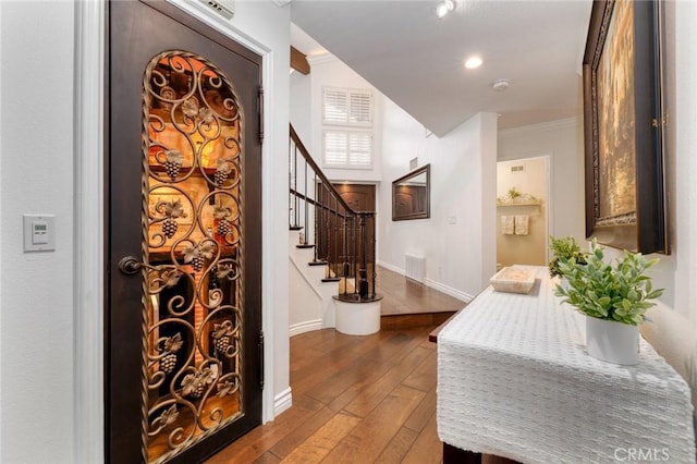 interior space with stairway, dark wood-style floors, visible vents, ornamental molding, and baseboards