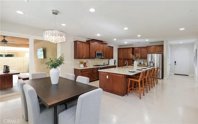 213 Wicker, Irvine, CA 92618 - kitchen featuring appliances with stainless steel finishes, a breakfast bar area, light countertops, a sink, and a kitchen island with sink