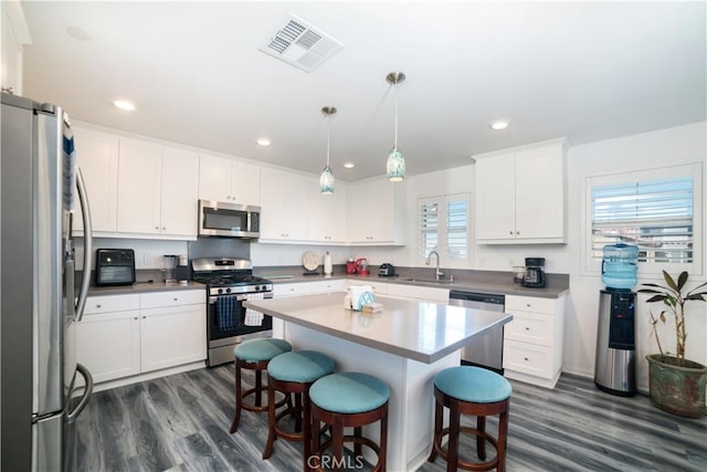 kitchen featuring visible vents, a kitchen breakfast bar, stainless steel appliances, and dark wood-style floors