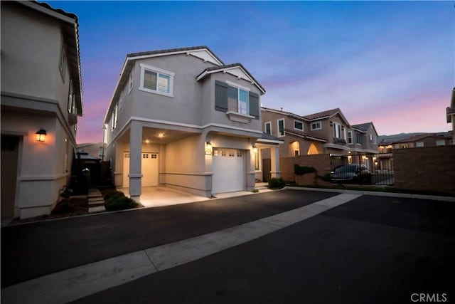 view of front of house featuring stucco siding, an attached garage, driveway, and fence