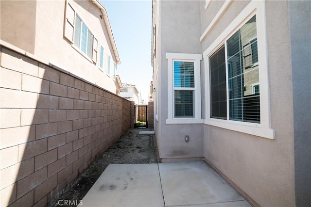 view of property exterior with stucco siding, a patio, and fence