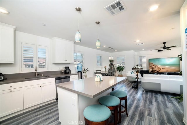 kitchen featuring a center island, a sink, plenty of natural light, dark wood finished floors, and visible vents