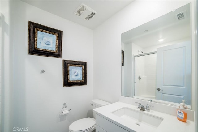 full bath with vanity, toilet, a shower with door, and visible vents