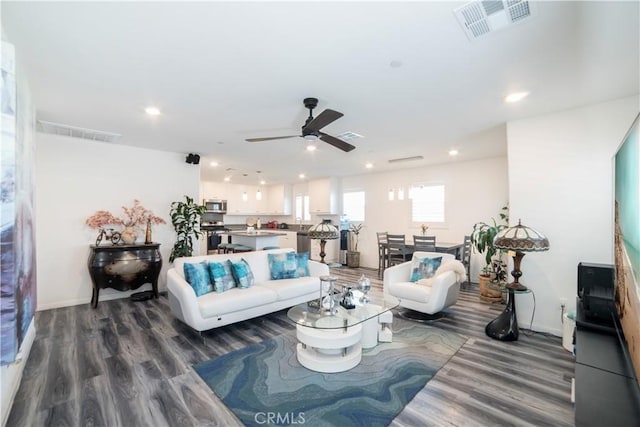 living area featuring dark wood-type flooring, visible vents, a ceiling fan, and recessed lighting