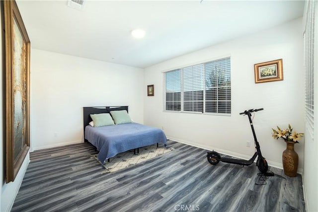 bedroom with baseboards, wood finished floors, and visible vents