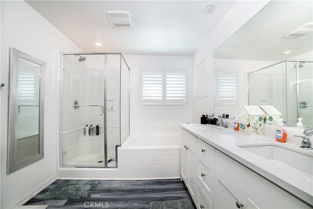 bathroom with a shower stall, a garden tub, a sink, and visible vents