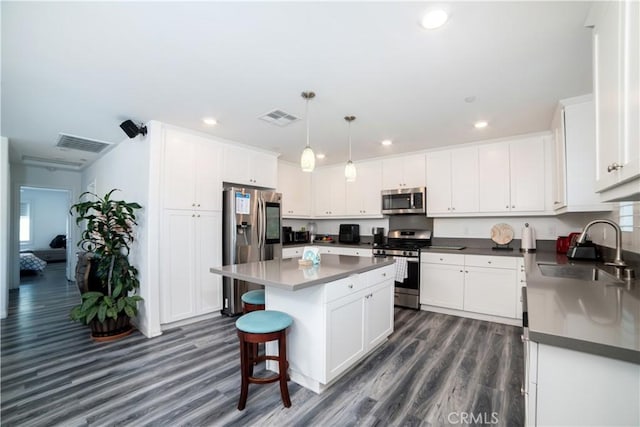 kitchen with white cabinets, dark wood finished floors, visible vents, a sink, and appliances with stainless steel finishes