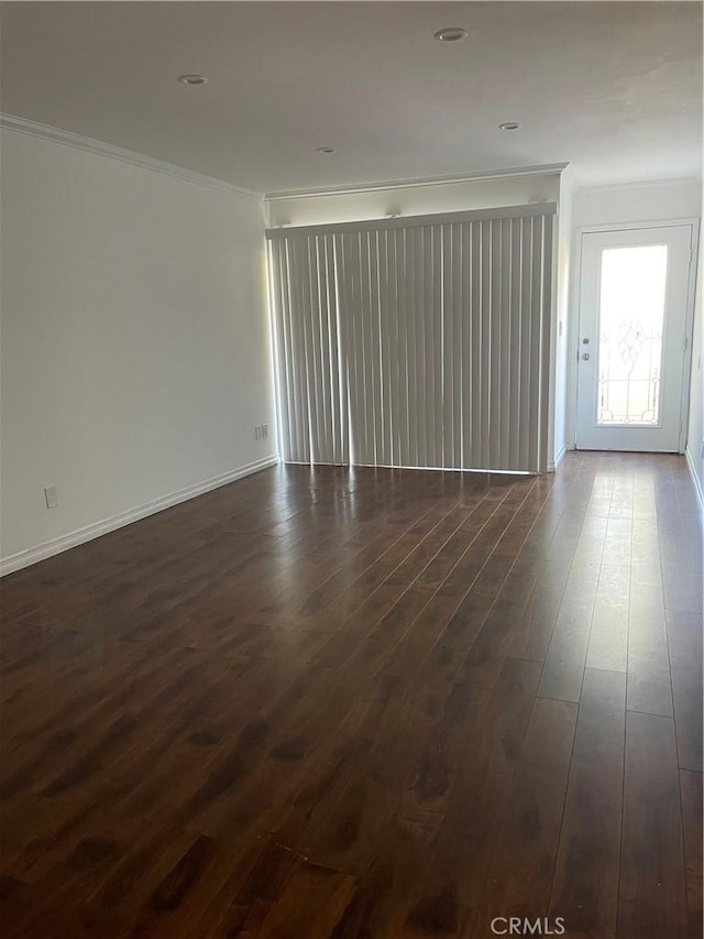 unfurnished living room with crown molding, dark wood-style flooring, and baseboards