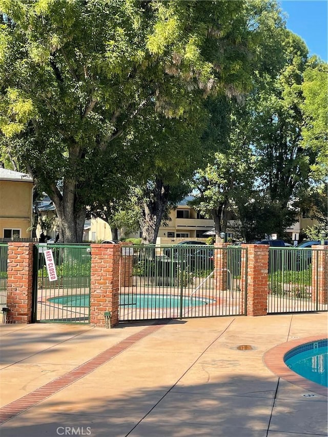 view of gate featuring fence and a community pool