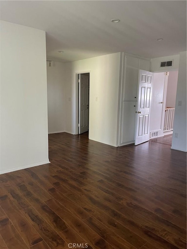 empty room with baseboards, dark wood finished floors, and visible vents