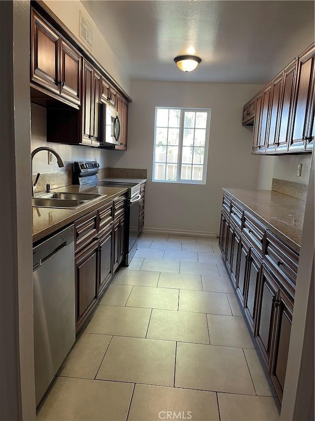 kitchen with dark countertops, appliances with stainless steel finishes, dark brown cabinetry, a sink, and visible vents