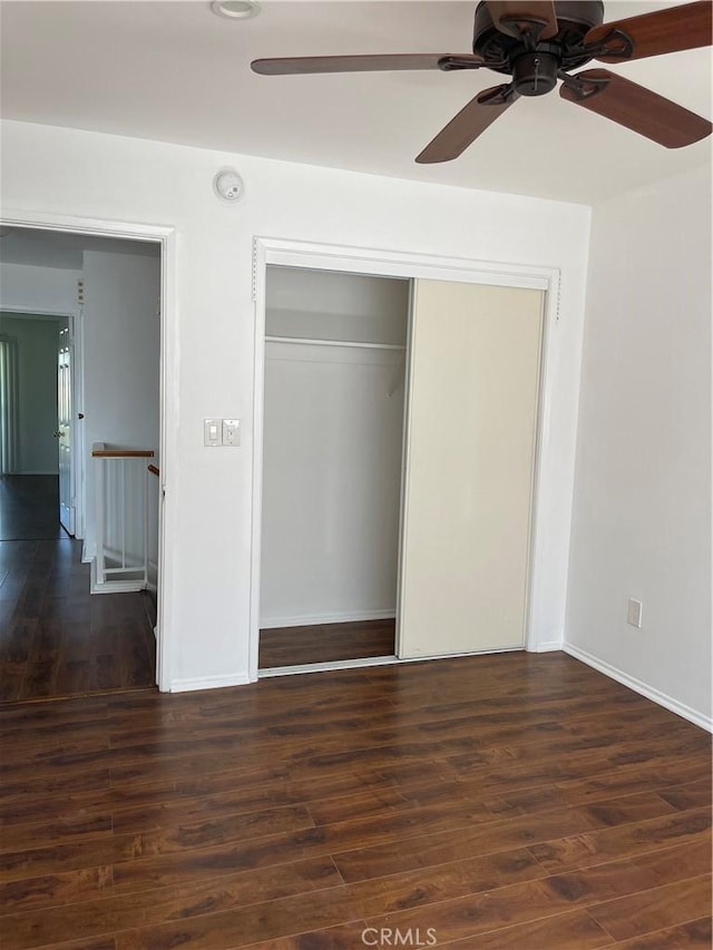 unfurnished bedroom featuring baseboards, ceiling fan, wood finished floors, and a closet